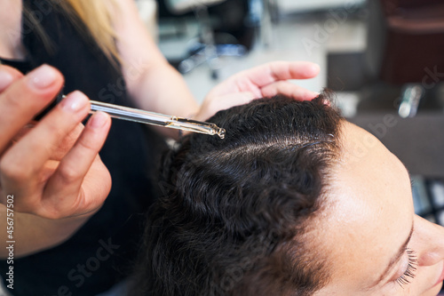 Close up of woman dropping serum on hair