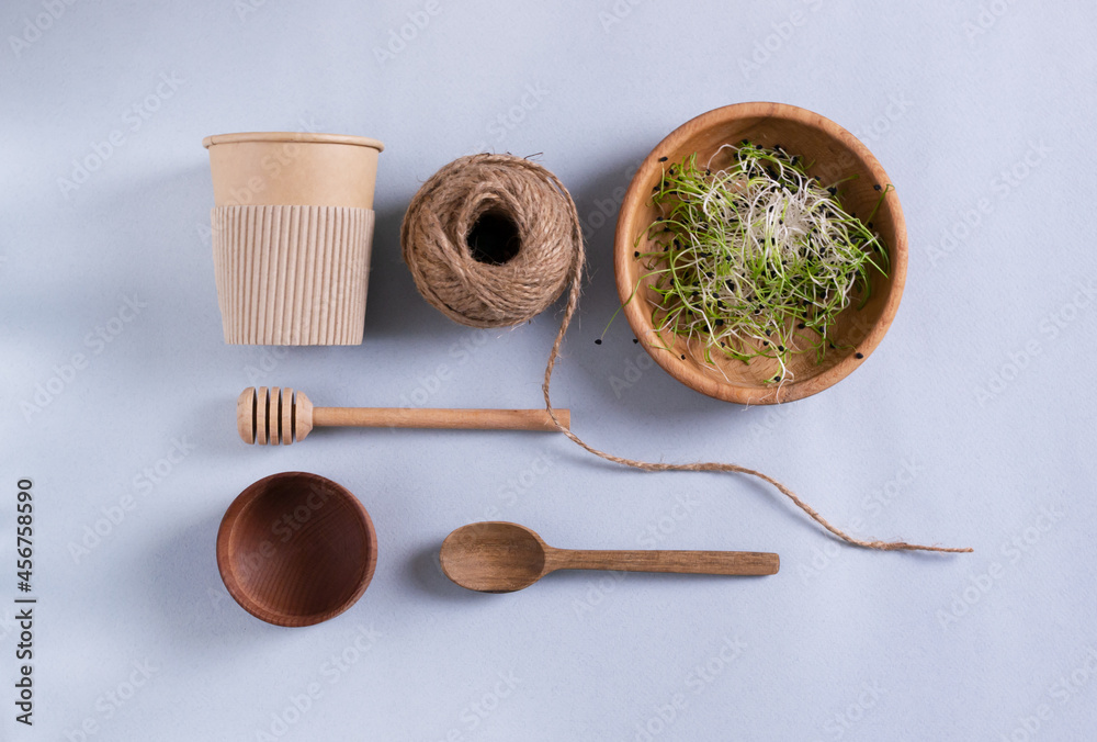 Paper cup, burlap jute, wooden bowl with micro greens, honey spoon, teaspoon. Eco friendly stuff concept. Horizontal orientation. Top view. Paper cup, burlap jute, wooden bowl with micro greens, honey spoon, teaspoon. Eco friendly stuff concept. Horizontal orientation. Top view.