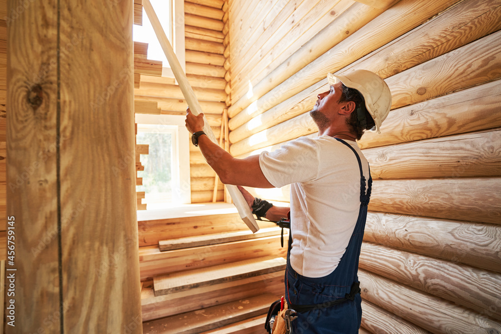 Man applying wooden board to staircase wall Man applying wooden board to staircase wall