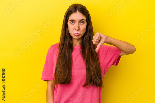 Young caucasian woman isolated on yellow background showing a dislike gesture, thumbs down. Disagreement concept.