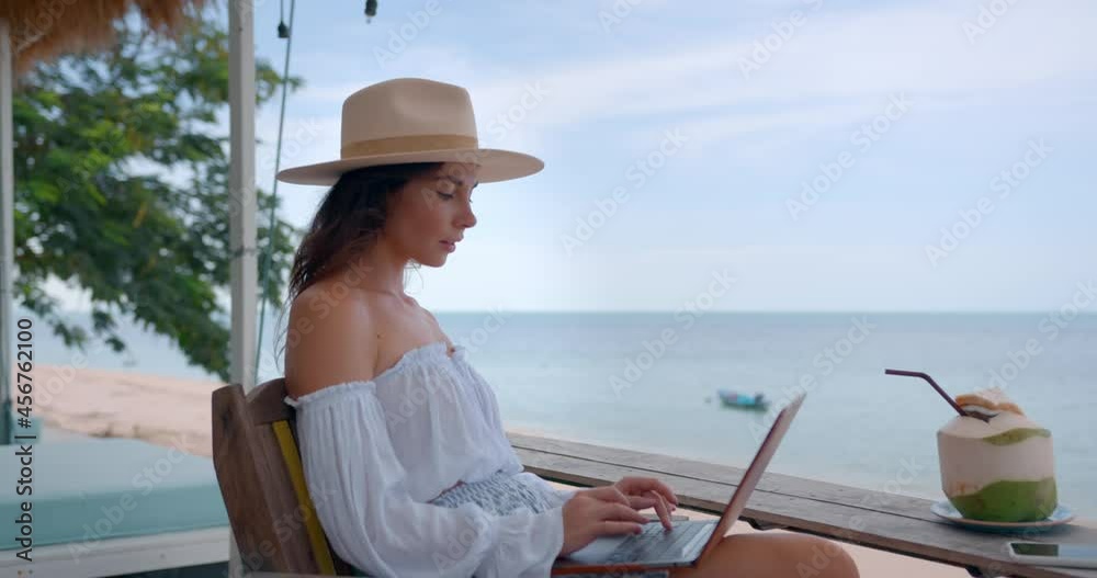 Young caucasian female typing the text on compact computer at beach cafe outdoors Young caucasian female typing the text on compact computer at beach cafe outdoors