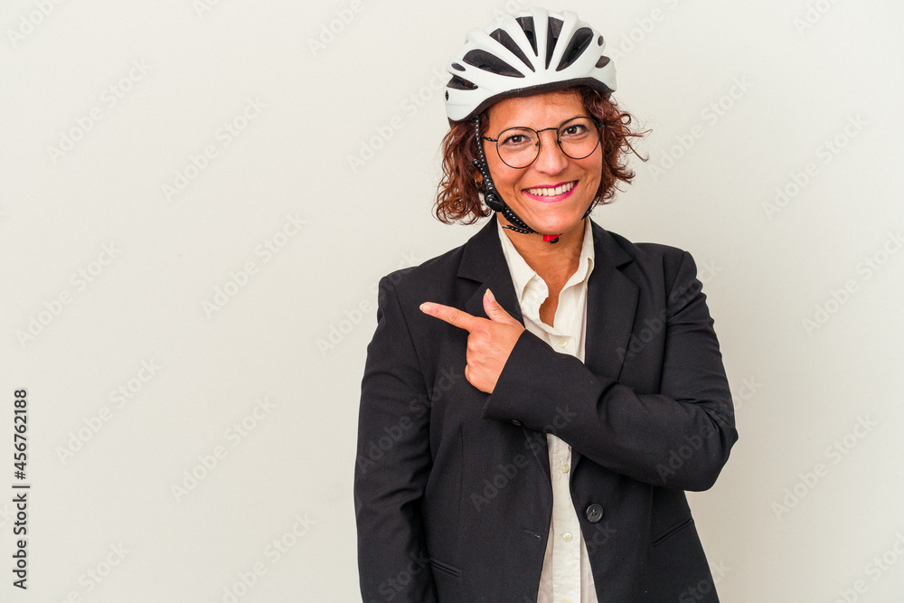 Middle age latin business woman wearing a bike helmet isolated on white background smiling and pointing aside, showing something at blank space. Middle age latin business woman wearing a bike helmet isolated on white background smiling and pointing aside, showing something at blank space.