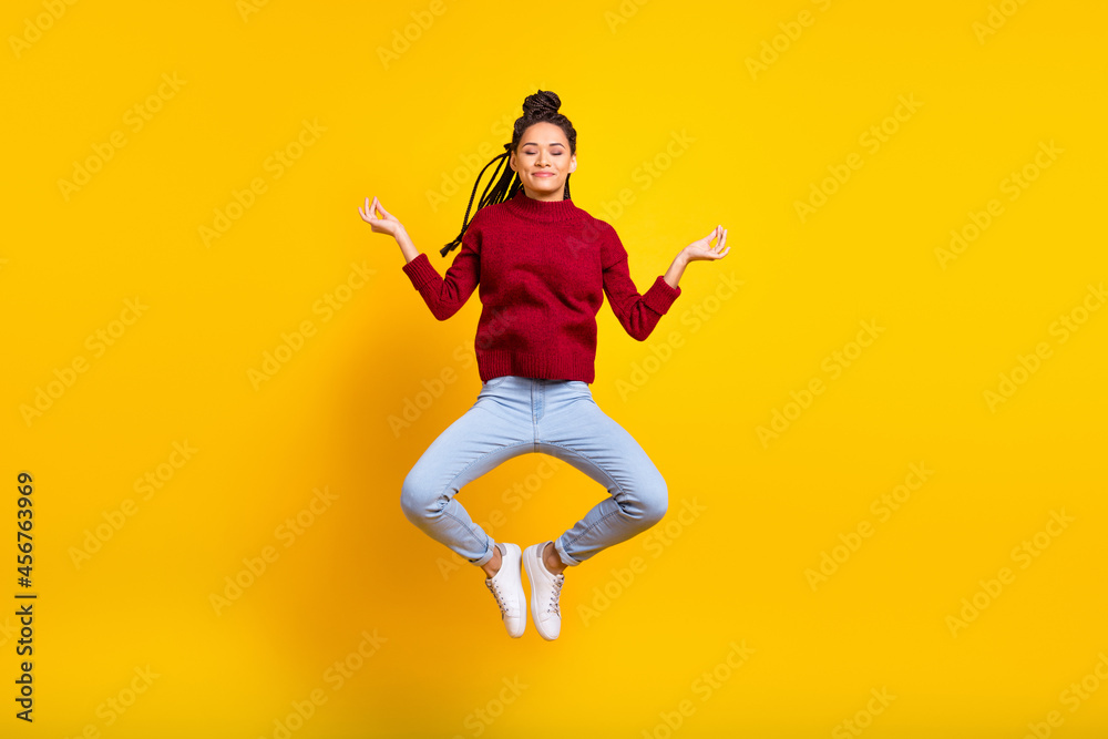 Full length high of shiny charming dark skin woman dressed red sweater jumping practicing yoga isolated yellow color background