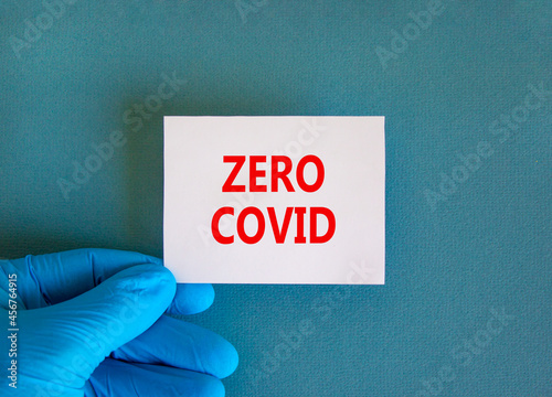 Covid-19 zero covid symbol. White note with words zero covid, beautiful blue background, doctor hand in blue glove. Medical and Covid-19 zero covid concept. photo