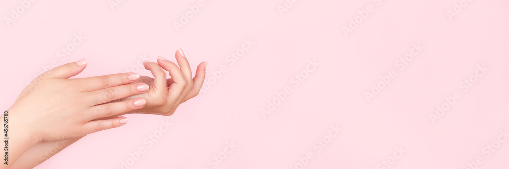 Female hands with beautiful manicure - pink nude nails on pink background, wide panoramic banner with copy space. Nail care concept Female hands with beautiful manicure - pink nude nails on pink background, wide panoramic banner with copy space. Nail care concept