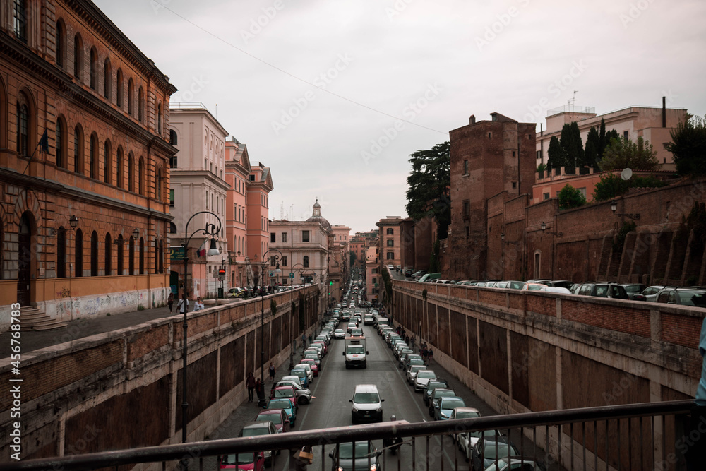 A city-scape shot of a Rome lowered level street with orange buildings around on a cloudy day