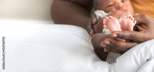 Blurred soft images, Hand of father holding  Baby's foot of African black skin baby newborn, concept to showing love and concern for his children, And is love family relationship.