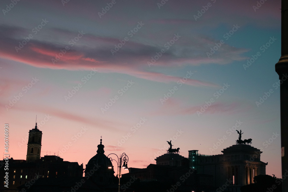 A colorful sunset sky above Italy Rome with landmarks in shade
