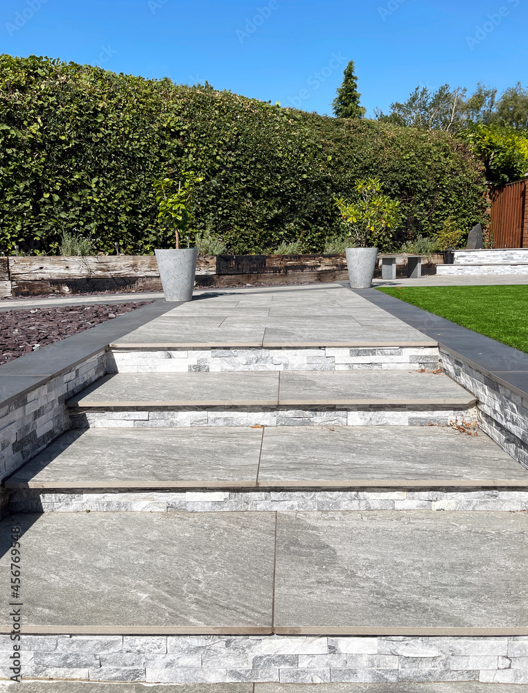 Steps in a private garden formed using porcelain paving slabs in contrasting light and dark grey. No people.