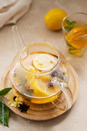 Glass tea pot with fruit delicious herbal tea on bright background.