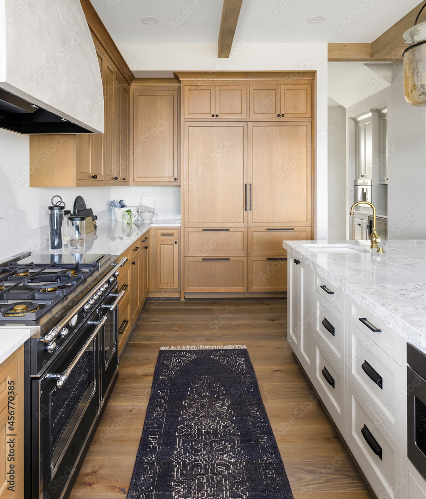 Kitchen detail in new luxury home. Features large island with faucet, large gas  range and oven, large range hood and built in refrigerator. Stock Photo |  Adobe Stock