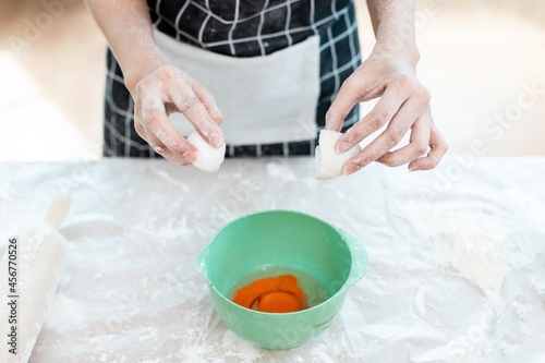 A woman is mixing flour and eggs in a bowl before kneading the dough to make bread.