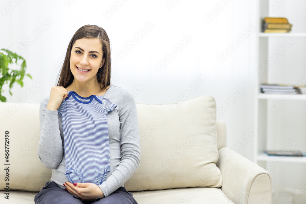 Photo of pregnant woman holding child small clothes.