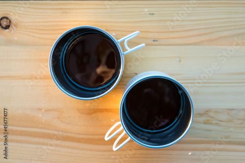 two coffee cup put on wood table with morning sunlight and mountain background