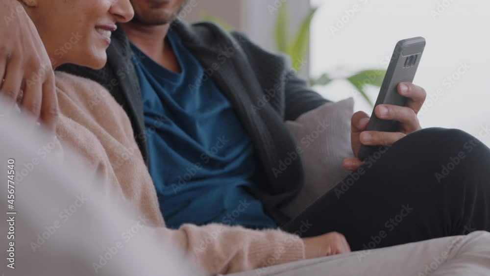 happy couple relaxing at home using smartphone together shopping online enjoying browsing internet relaxing on couch happy couple relaxing at home using smartphone together shopping online enjoying browsing internet relaxing on couch