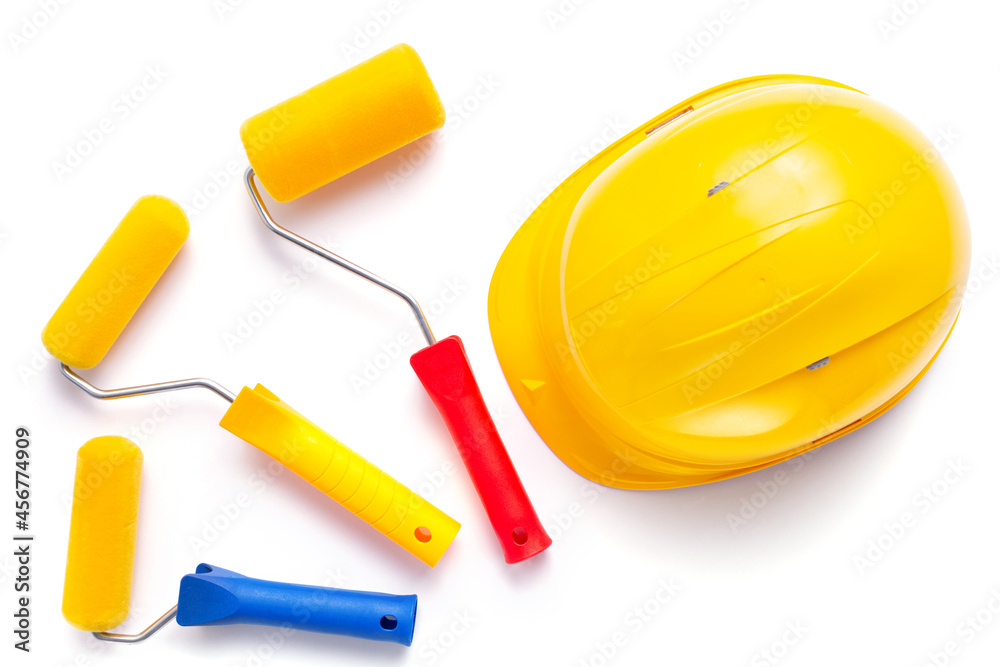 Paint roller and hard hat isolated at white background. Construction helmet with tool