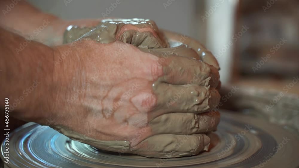 slow motion of ceramic craftsman's hands begin to shape a clay pot on the potter's wheel slow motion of ceramic craftsman's hands begin to shape a clay pot on the potter's wheel