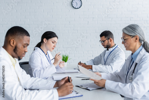 multicultural doctors sitting at desk during medical council in clinic