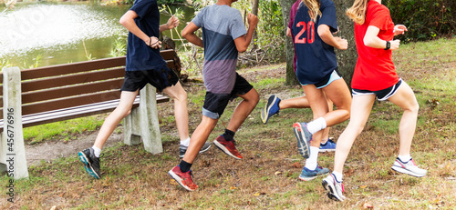 Boys and girls running together around a lake in a park