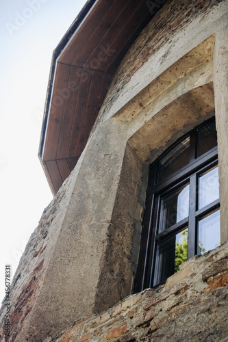 The wall of an old building made of red brick and stone. Window in the tower of an ancient castle