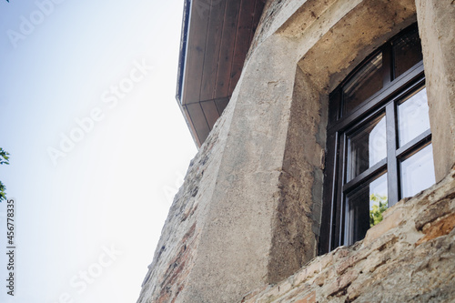 The wall of an old building made of red brick and stone. Window in the tower of an ancient castle