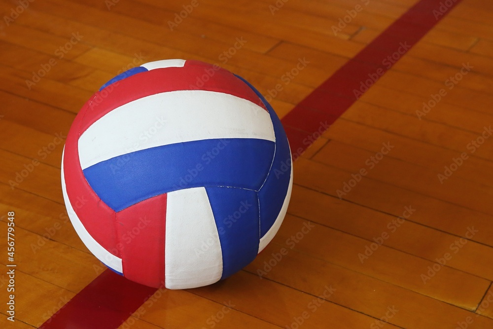 red, white, and blue volleyball on wooden gym floor