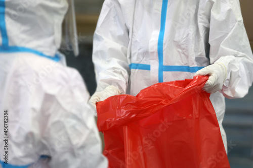 Medical waste or Clinical waste disposal is a hazardous waste clear used PPE suit (Personal Protective Equipment)  medical masks gloves face shield and sock in Red Garbage Plastic bag