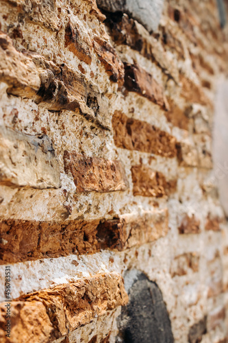 The wall of an old building made of red brick and stone. Brick wall close-up