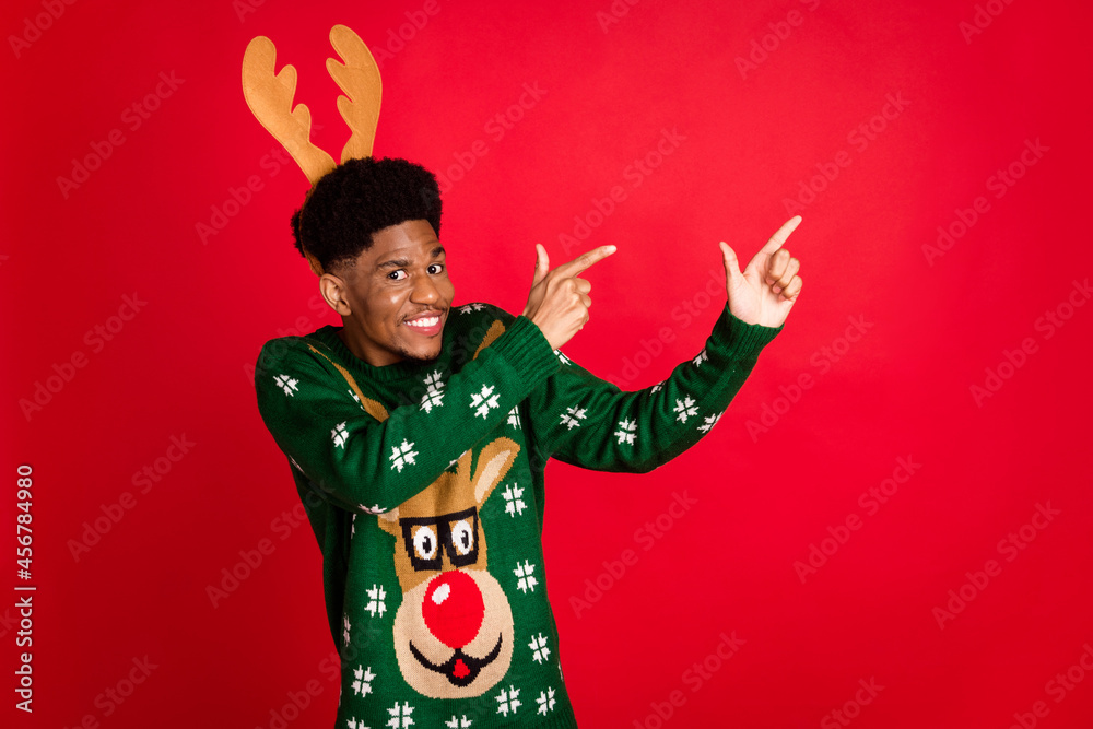 Portrait of attractive childish guy wearing festal horns demonstrating copy space gift isolated over bright red color background Portrait of attractive childish guy wearing festal horns demonstrating copy space gift isolated over bright red color background