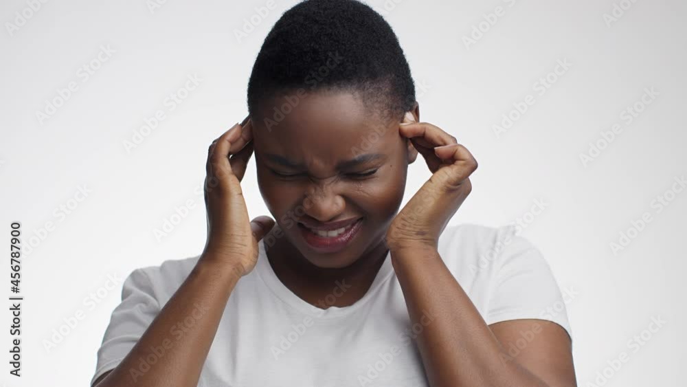 Migraine attack. Young stressed african american woman suffering from acute headache, massaging her temples Migraine attack. Young stressed african american woman suffering from acute headache, massaging her temples