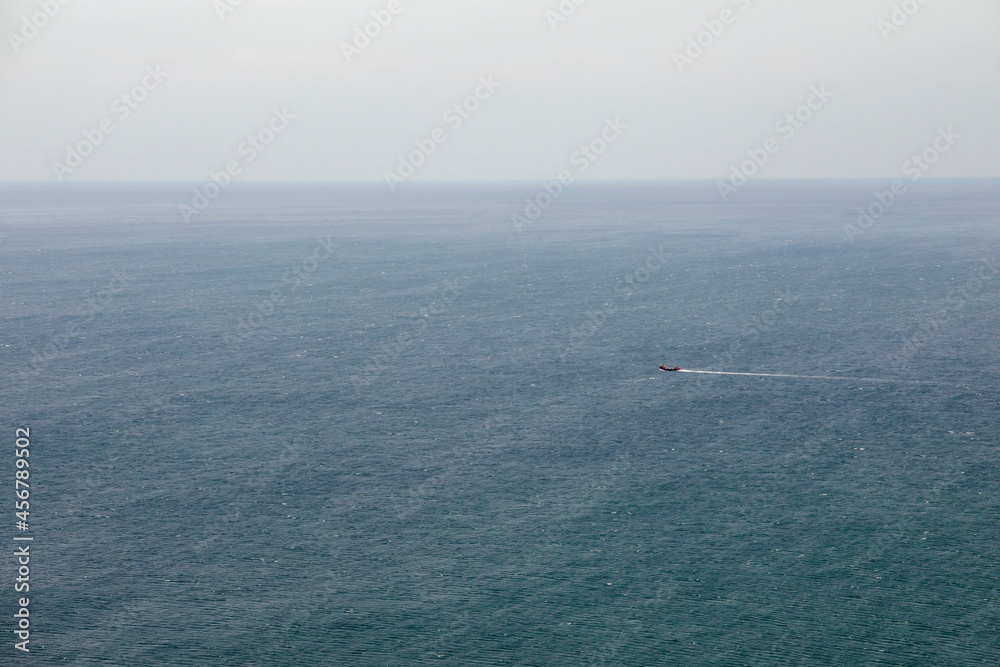 Blue smooth surface of the Black Sea. Lonely sailing ship. Minimalistic landscape.