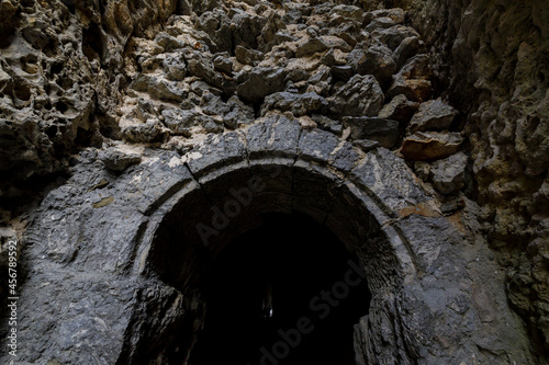 Stone-framed entrance to the grotto. Through cave. Dark scary space.