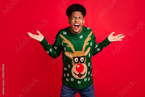 Photo of crazy angry guy open mouth scream close eyes wear christmas sweater isolated on red background