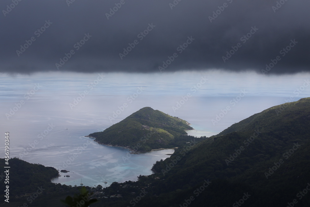 Black clouds over the mountains on the coastline and the sea.Stormy skies covered the green island and lagoon.Background image of tropical gloomy rainy day aerial view Black clouds over the mountains on the coastline and the sea.Stormy skies covered the green island and lagoon.Background image of tropical gloomy rainy day aerial view