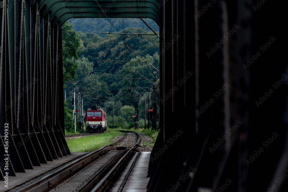 Passenger train with red electric locomotive and passenger coaches in summer