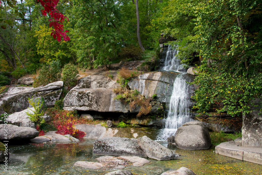 Fototapeta premium stone mountain waterfall and lake. A picturesque cascade waterfall among large stones in the Landscape Park, in spring or summer. big waterfalls, nature. Europe, Ukraine, Uman, Sofiyivka arboretum