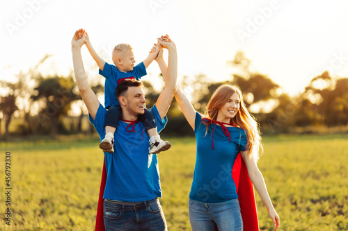 concept of european superfamily, outdoors, loving father holds on the neck, superhero family run at sunset in nature