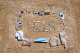 Nature asks for help from pollution. The word HELP from small seashells in the sand. Garbage is spread around.