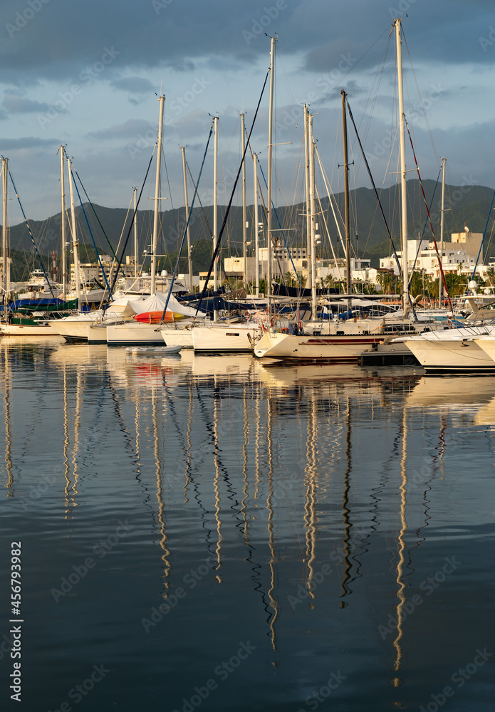 Many sailboats Docked at a Marina on dramatic sunrise background with mountains 