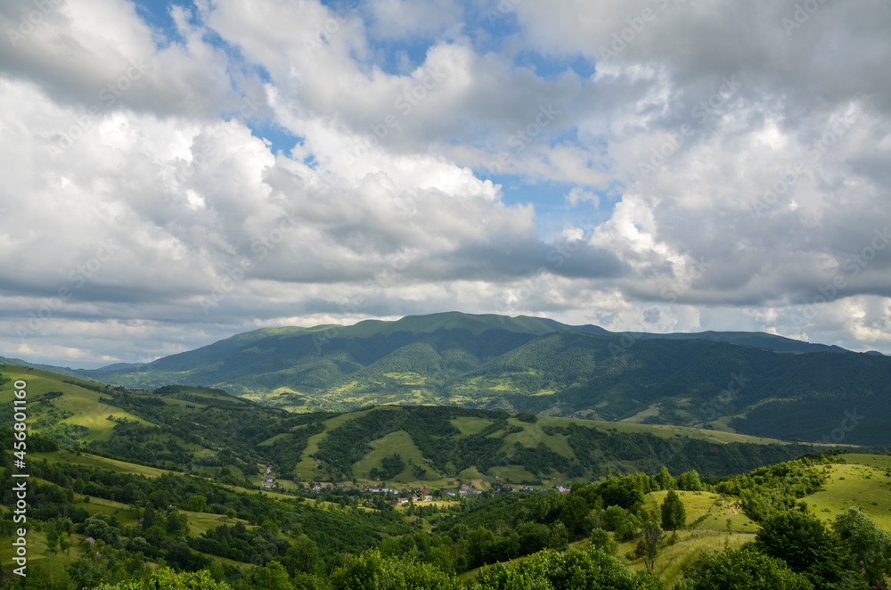 Picturesque summer scenery of rolling countryside with rural houses of a small village on green hills. Carpathian Mountains, Ukraine Picturesque summer scenery of rolling countryside with rural houses of a small village on green hills. Carpathian Mountains, Ukraine
