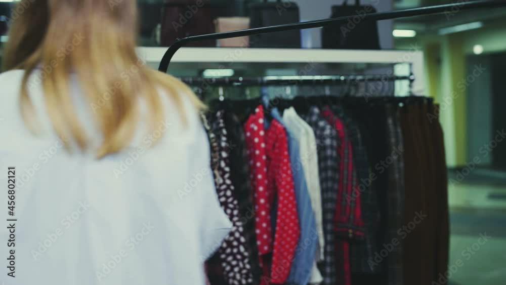A pretty girl takes all the things from the hanger and takes them away. Shopping trip