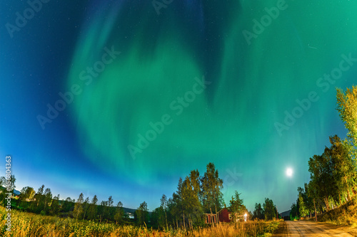 Northern Lights above small village street in Swedish Mountains. One of the best place to see the Aurora Borealis  green lights all over the sky.