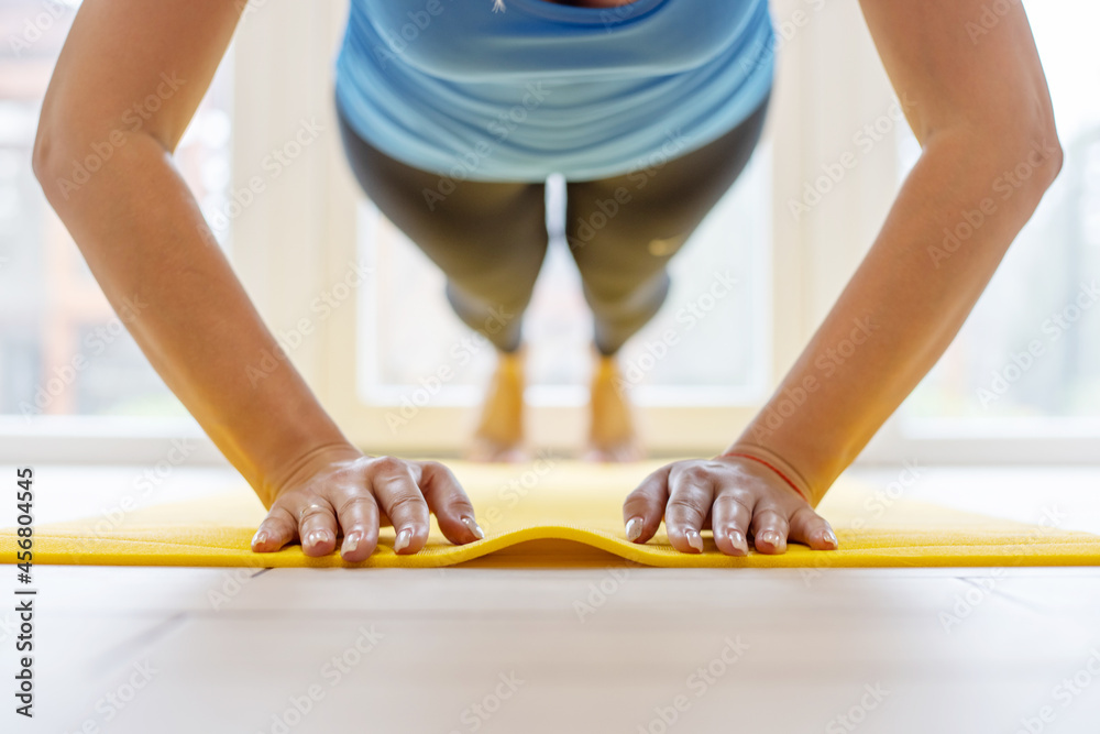 Young sports woman in sportswear on a yoga mat doing push ups or pushing exercises. Weight loss, healthy lifestyle concept