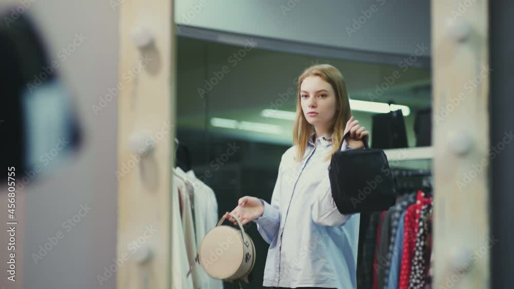 A pretty girl tries on handbags to her style of clothing. Shopping A pretty girl tries on handbags to her style of clothing. Shopping