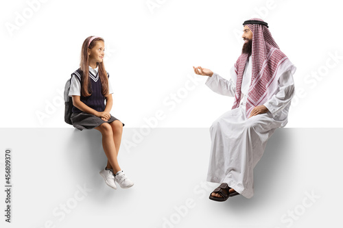 Schoolgirl sitting on a blank panel and listening to an arab man talking