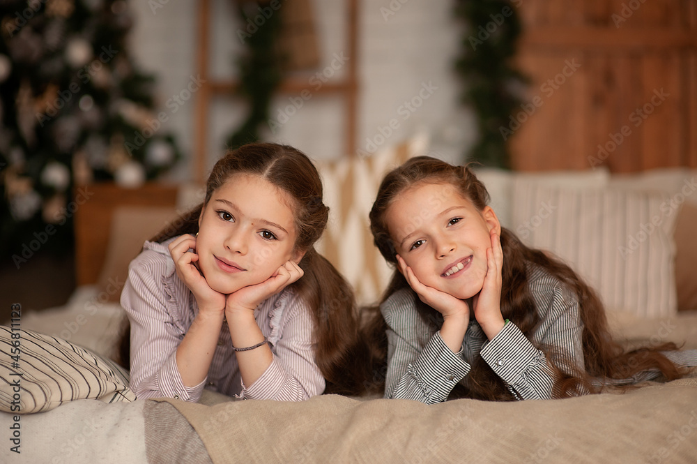 Two girls lie on the bed in the christmas bedroom interior Two girls lie on the bed in the christmas bedroom interior