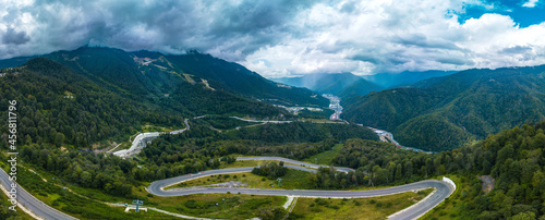 panorama of a mountain road, serpentine descending down a forested slope to the valley of the Mzymta river among the Caucasus mountains on a cloudy summer dayRussia, Caucasus, Sochi, summer, mountai