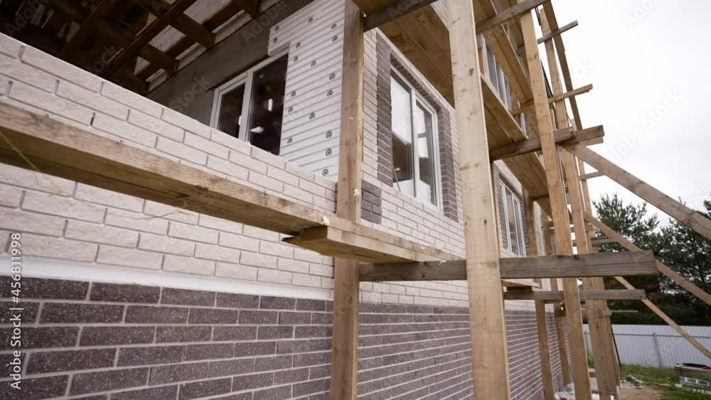 The wall of the house is built of brown and white bricks. Brick wall. The horizontal part of the wall is lined with white and yellow bricks. Brick background. Interior design and concept.