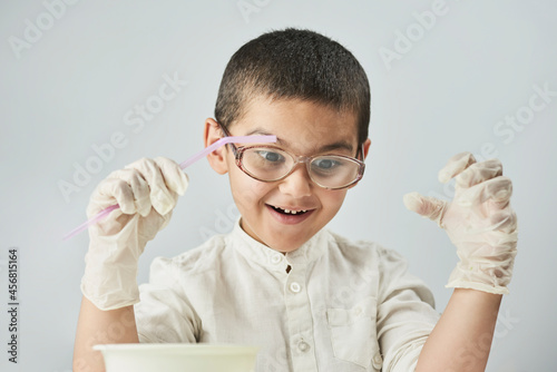 Funny kid making experiments at the workshop and exploring the world of chemistry against the white background