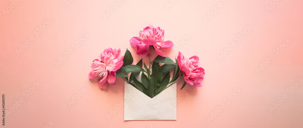 White envelope with pink peonies inside on a pink background. Template for newsletters and other mail designs